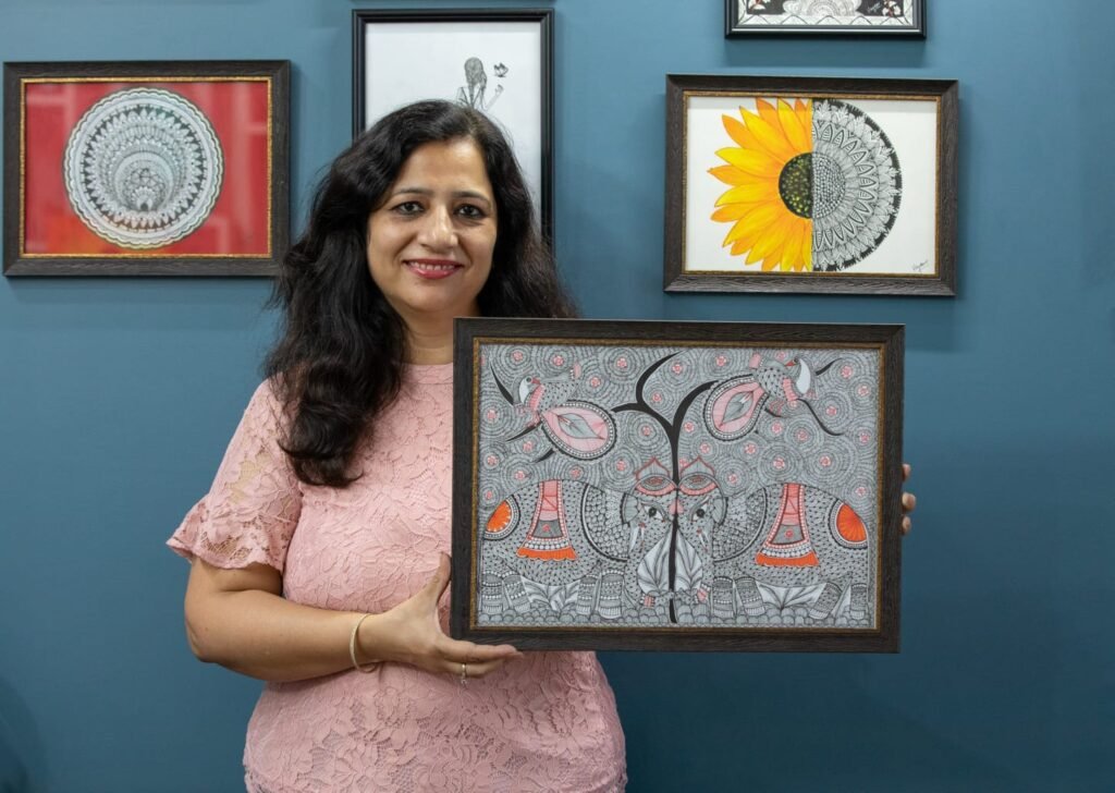 Vandana Bhasin holding one of her framed paintings