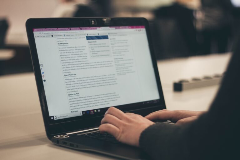 Hands typing on a laptop with a long article open on screen